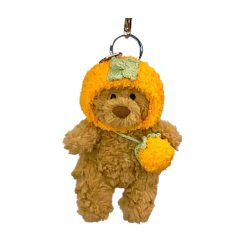 Jellycat Bartholomew Bear Bag Charm wearing a Persimmon-shaped headcover and holding a small matching bag.