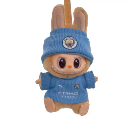 Labubu plush toy wearing a custom Manchester City Football Club jersey outfit with a chosen player number, including a sky blue replica jersey and a coordinating hat.