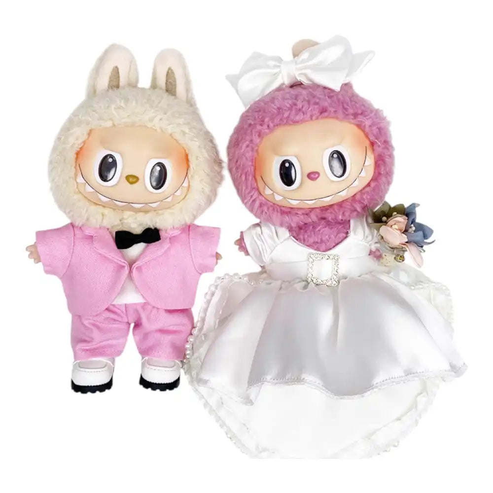 Labubu plush toys wearing a coordinated bridal outfit set. One Labubu wears a pink suit with jacket, shirt, bow tie, pants, and shoes. The other Labubu wears a white tulle dress with a headdress, necklace, and bouquet.