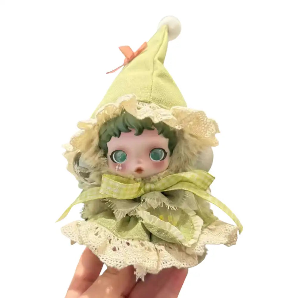 Skullpanda plush figure wearing the Forest Outfit, featuring a pale green gnome hat, a layered sage green and lace dress, and a lime green gingham ribbon accessory.